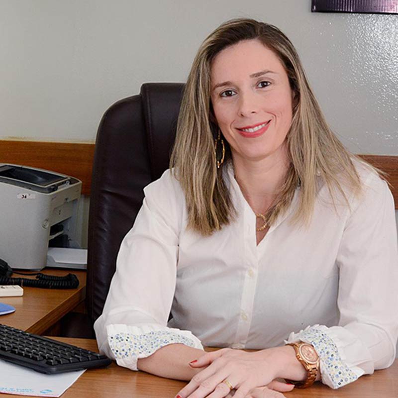 Janaína Rego, fisioterapeuta e responsável técnica, sentada à mesa do escritório